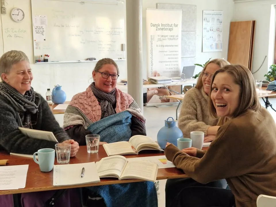 Fire studerende omkring bordet på zoneterapeutuddannelsen
